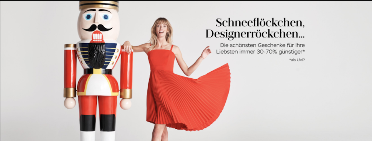Advertising billboard for McArthurGlen with woman in red dress next to a human sized nutcracker figure.