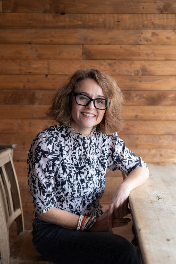 Picture of Anna van Ommen sat at a wooden table against wood panel wall.